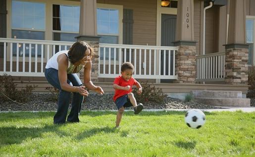 一位母亲和她的儿子在前院踢足球